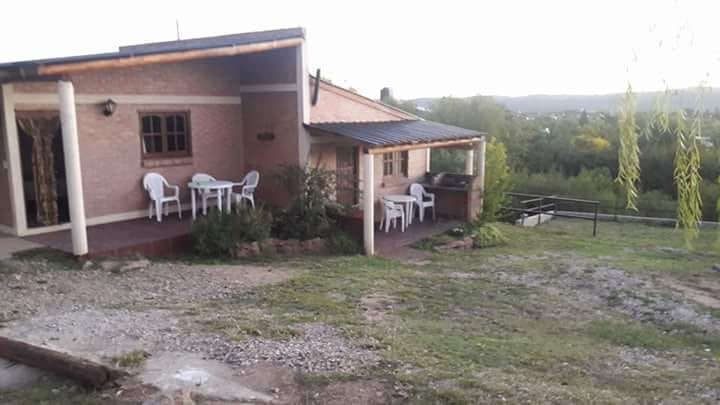Frente de una cabaña con mesa y sillas